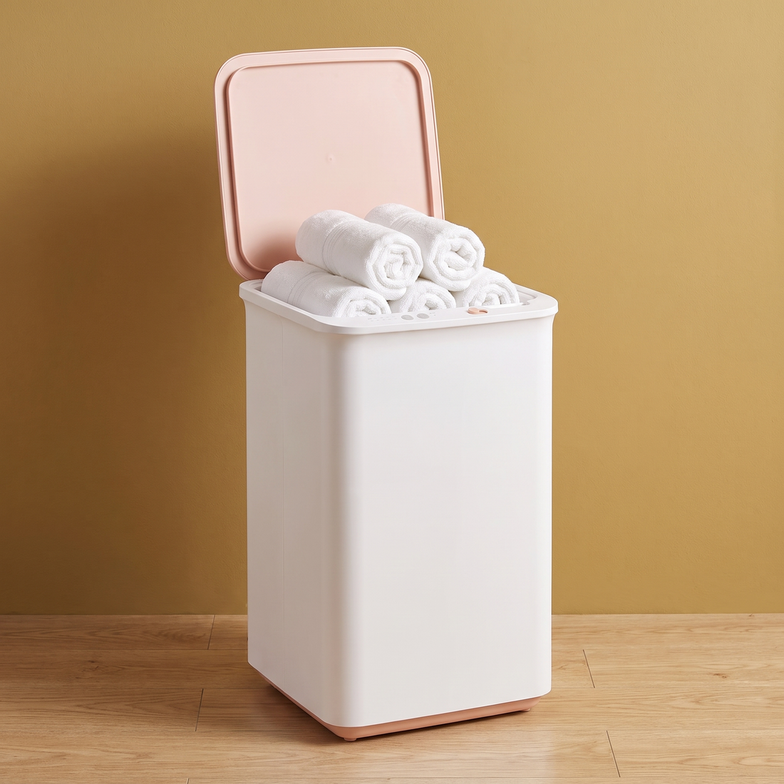 The Blush Spa towel warmer with rolled towels against a gold wall