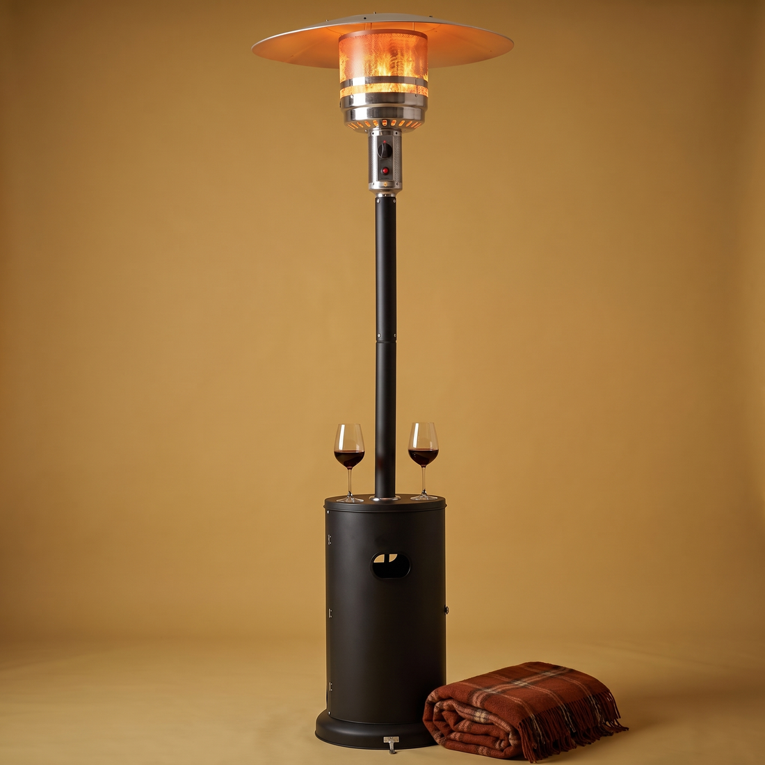 The Patio Classic 48,000 BTU propane patio heater in Black, lit, on a gold backdrop with wine glasses on its built-in table