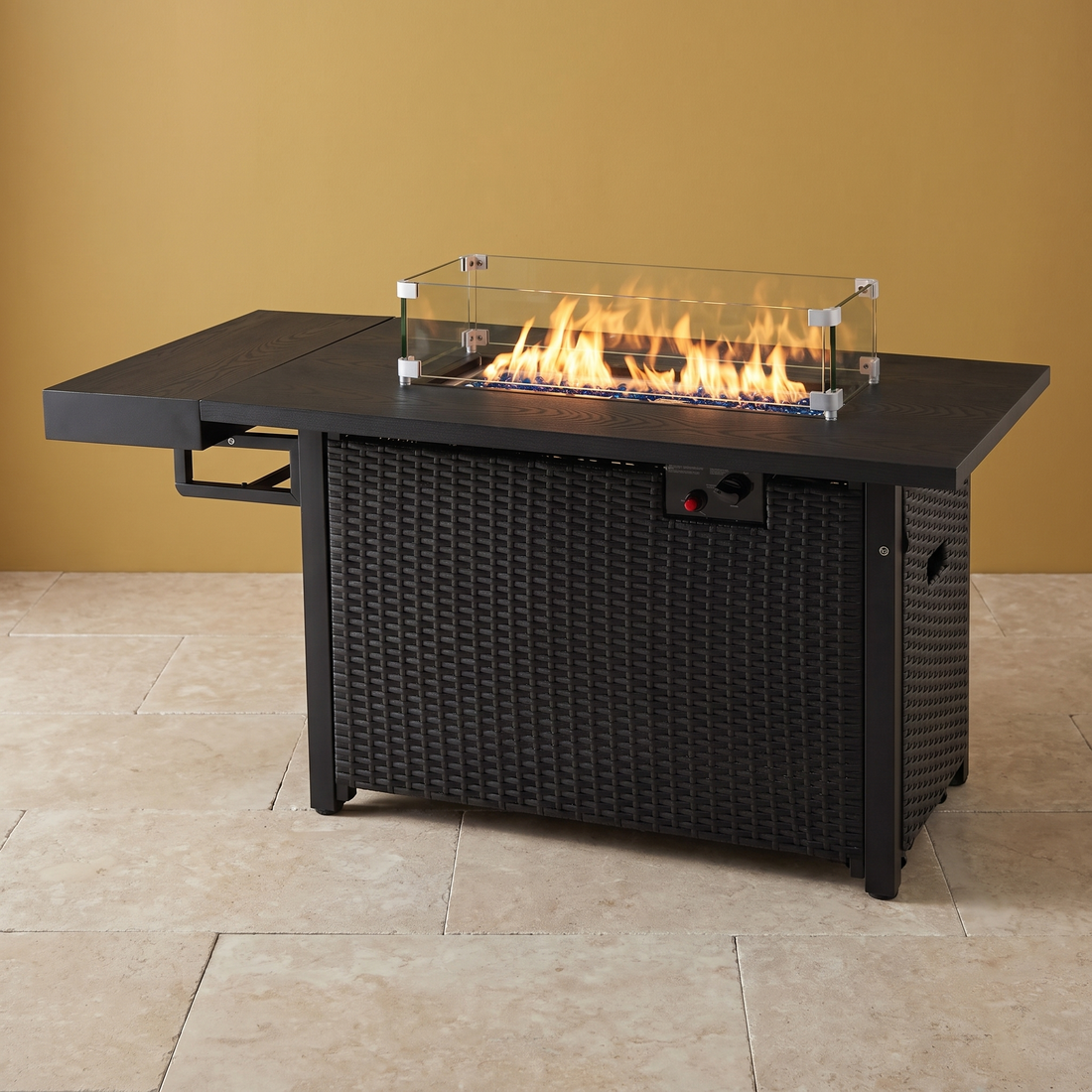 The Wicker Fire Table black propane fire pit table against a gold wall